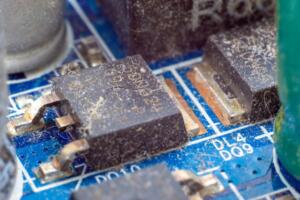 Close-up of a dirty electronic chip on a printed circuit board before ultrasonic cleaning.